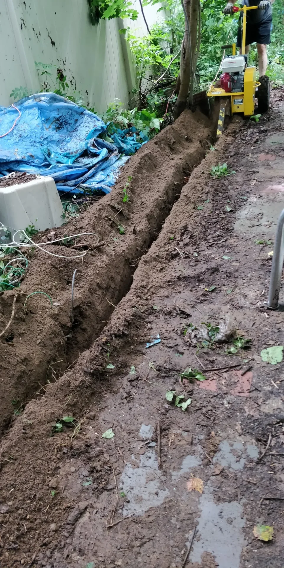 Trench dug for new PVC pool piping along the side of a house