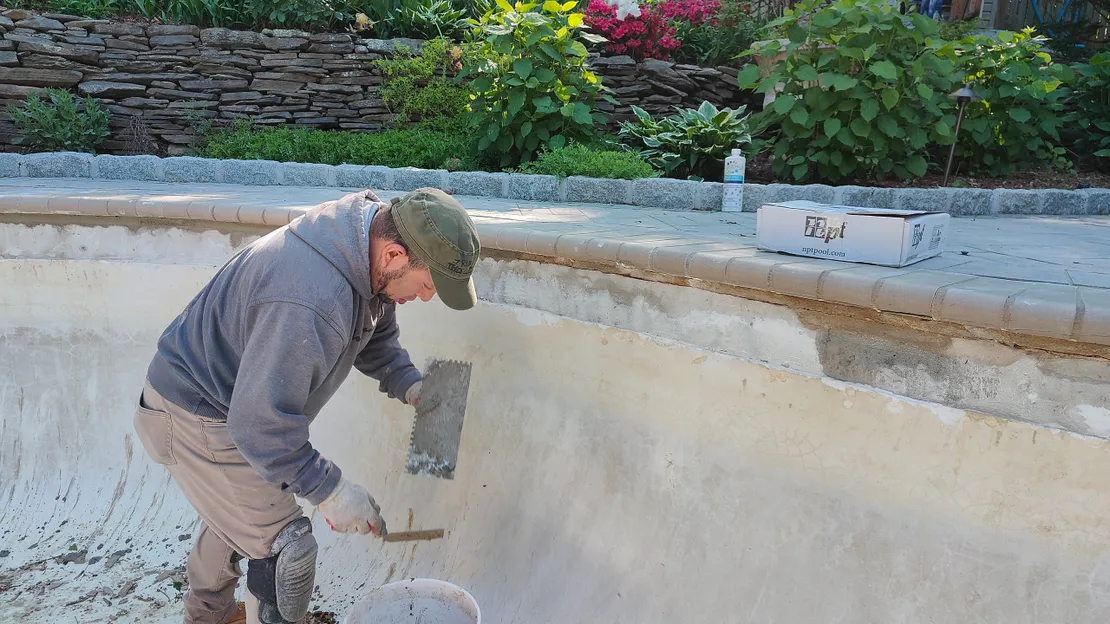 Worker applying fresh plaster to a pool wall with a trowel