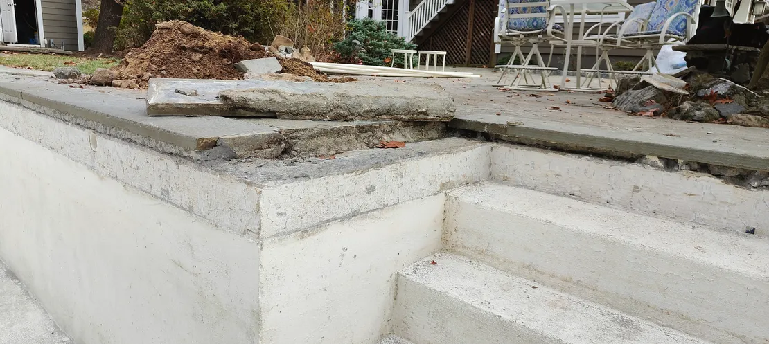 Damaged pool coping with broken concrete slabs being removed
