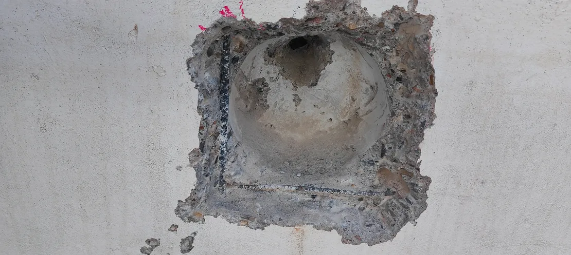 Old pool wall fitting patched with concrete during repair