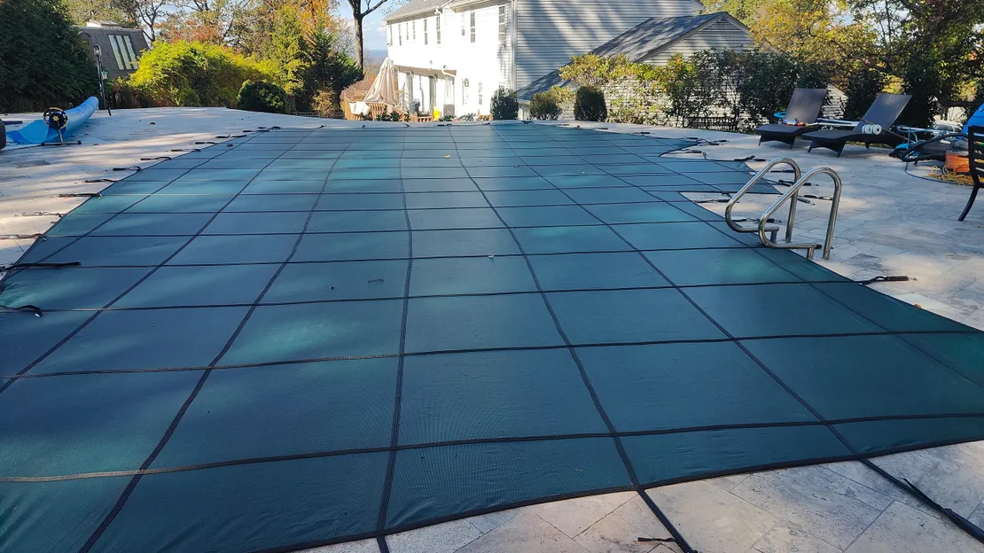 Green mesh safety cover installed on an inground pool